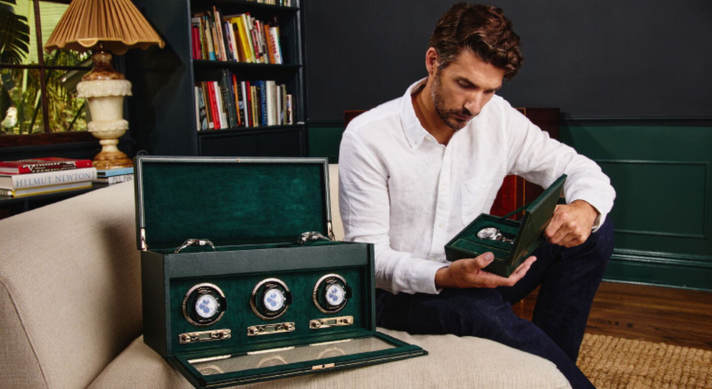A man holding a WOLF watch box with a watch winder beside him.